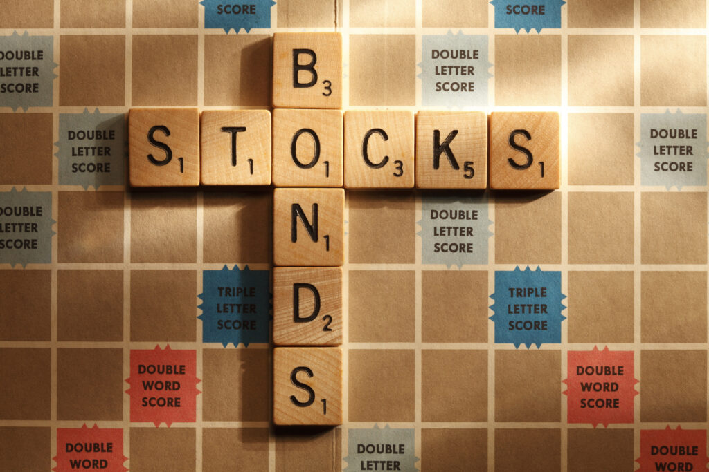 The words &quot;stocks&quot; and &quot;bonds&quot; spelled out on a Scrabble board and connected by the letter &quot;o&quot;