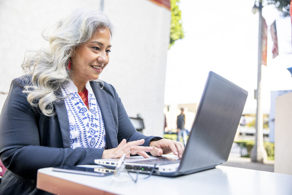 A woman smiles while working on her computer.