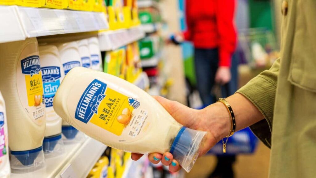 Lady taking a bottle of Hellmann's Real Mayonnaise from a supermarket shelf
