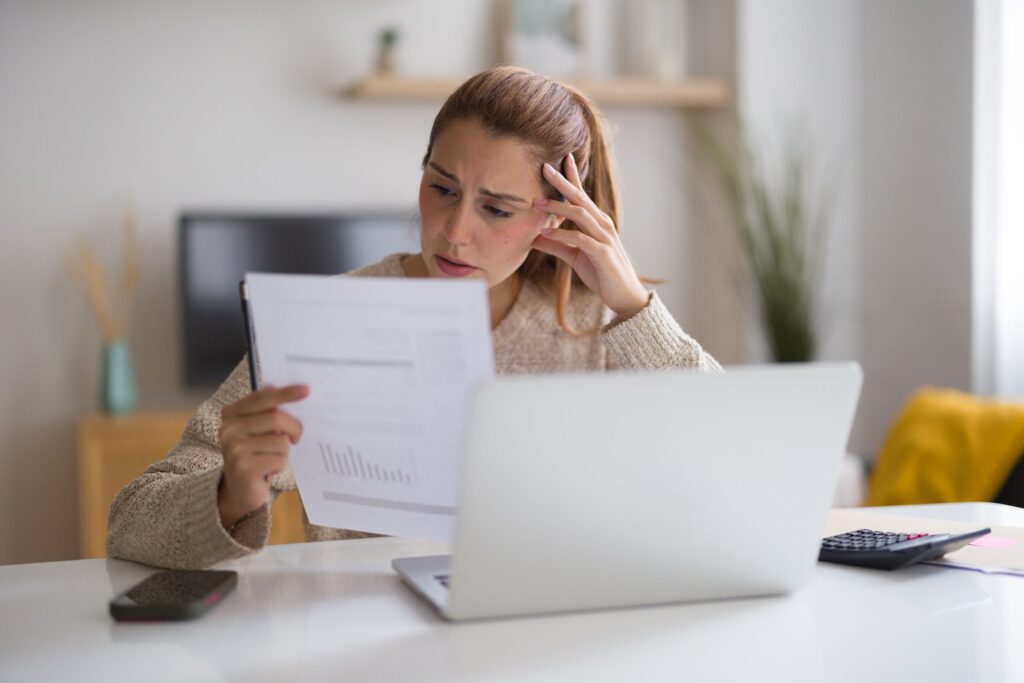 The Hidden Cost Driving Higher Electric Bills and Shorter Appliance Lifespans a woman surprised while reading a bill