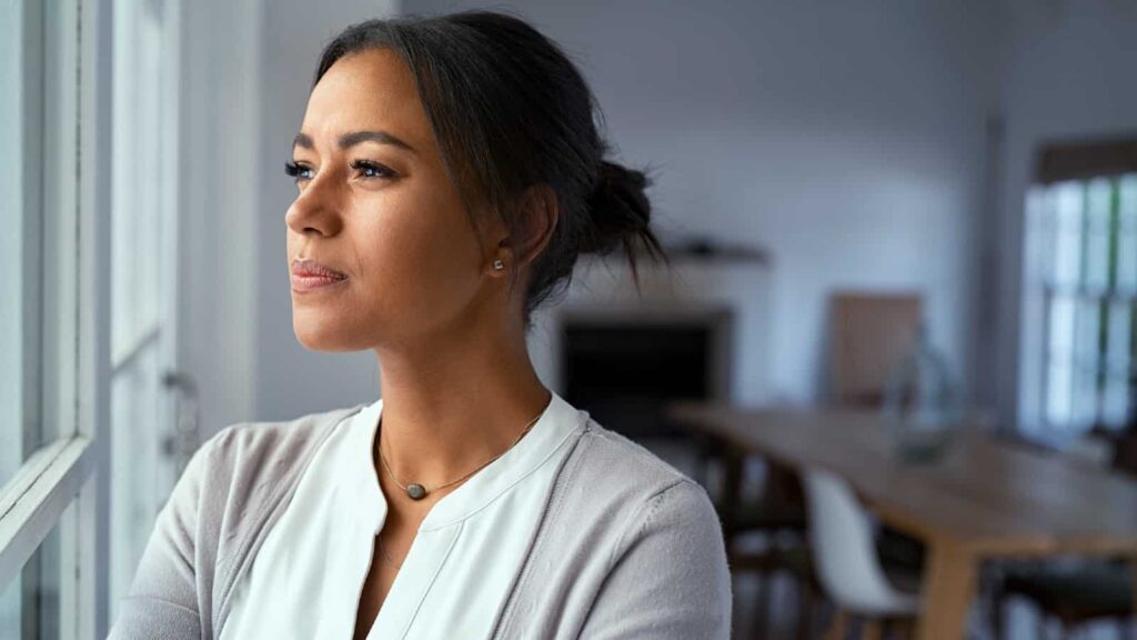 With stock market risks emerging, is now the time to consider the 60/40 portfolio? Young mixed-race woman looking out of the window with a look of consternation on her face