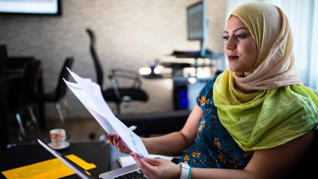 Is April a good time to start buying shares? Lady wearing a head scarf looks over pages on company financials